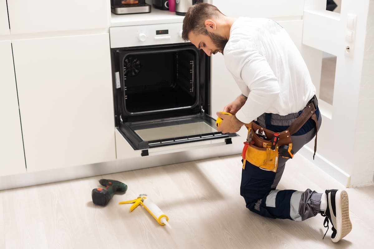 51091026 Man Repairing Domestic Oven In Kitchen